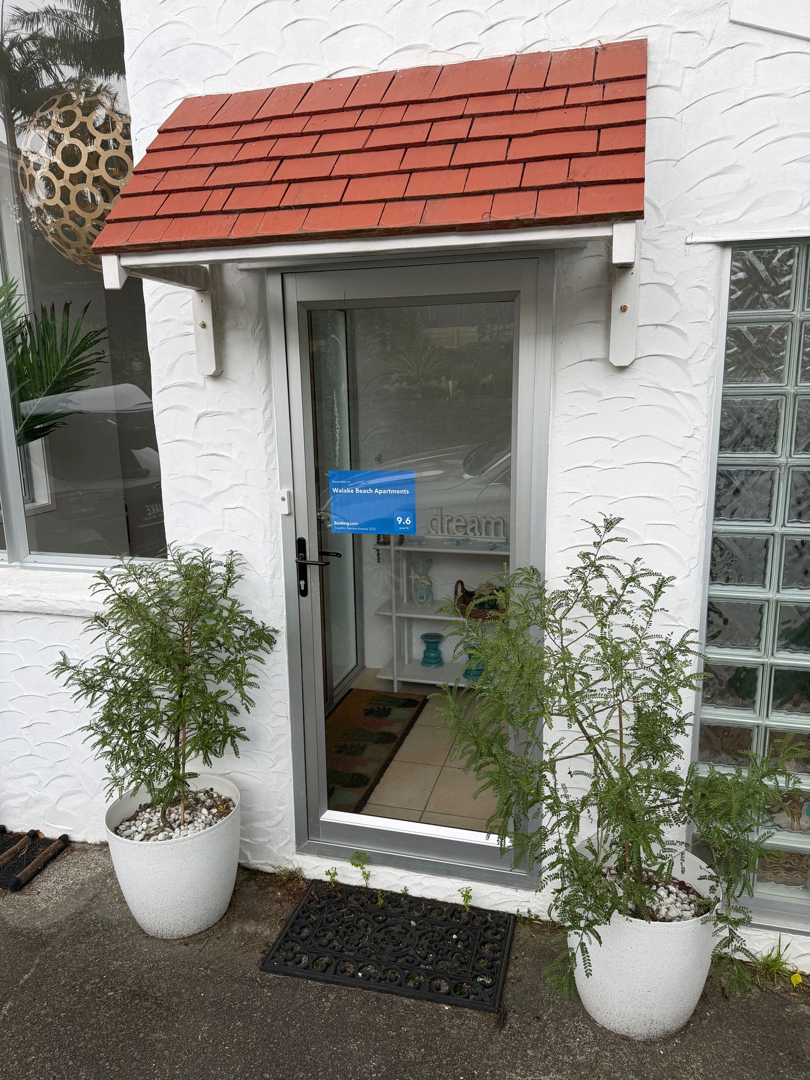 The front door under its red-tiled porch, potted ferns either side