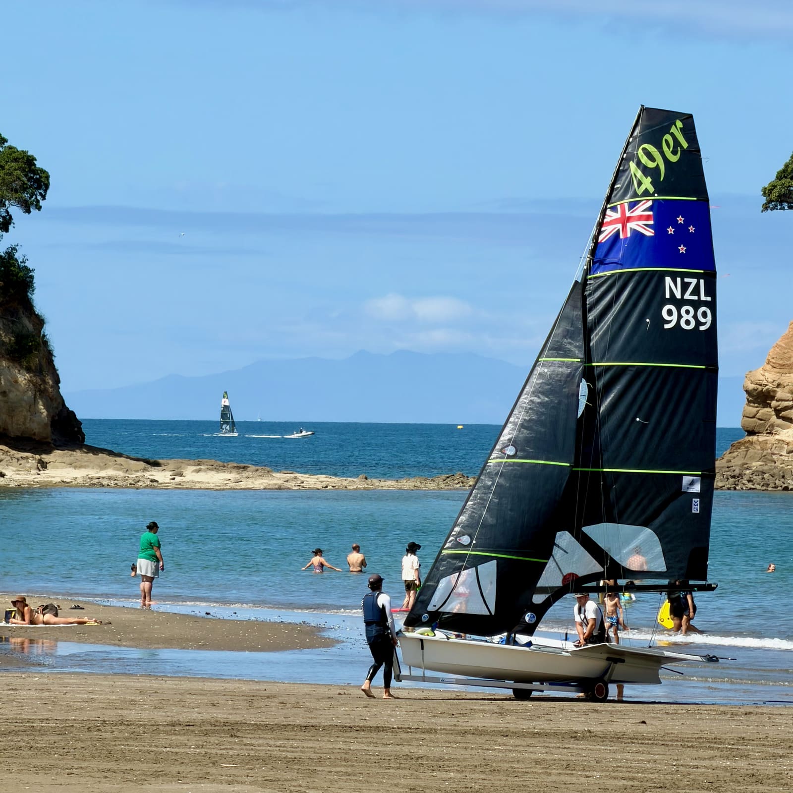 A 49er skiff on Waiake Beach with the Tor behind