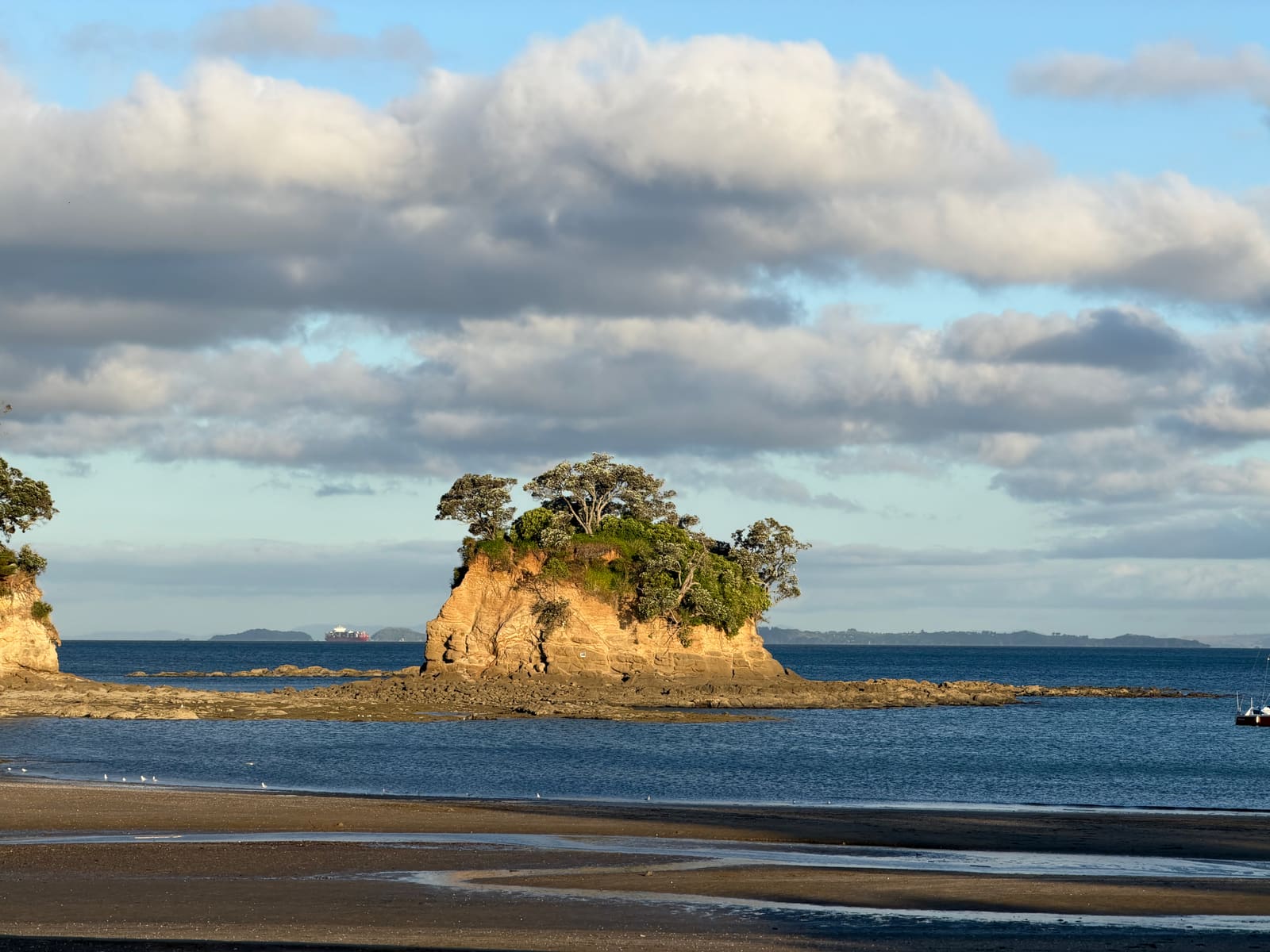 The Tor under cumulus cloud, a red yacht moored beside it