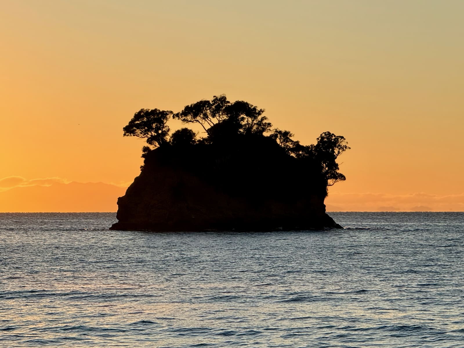 The Tor silhouetted against an orange sky, calm sea